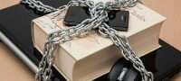A CHAIN HOLDING A PHONE, COMPUTER AND BOOK